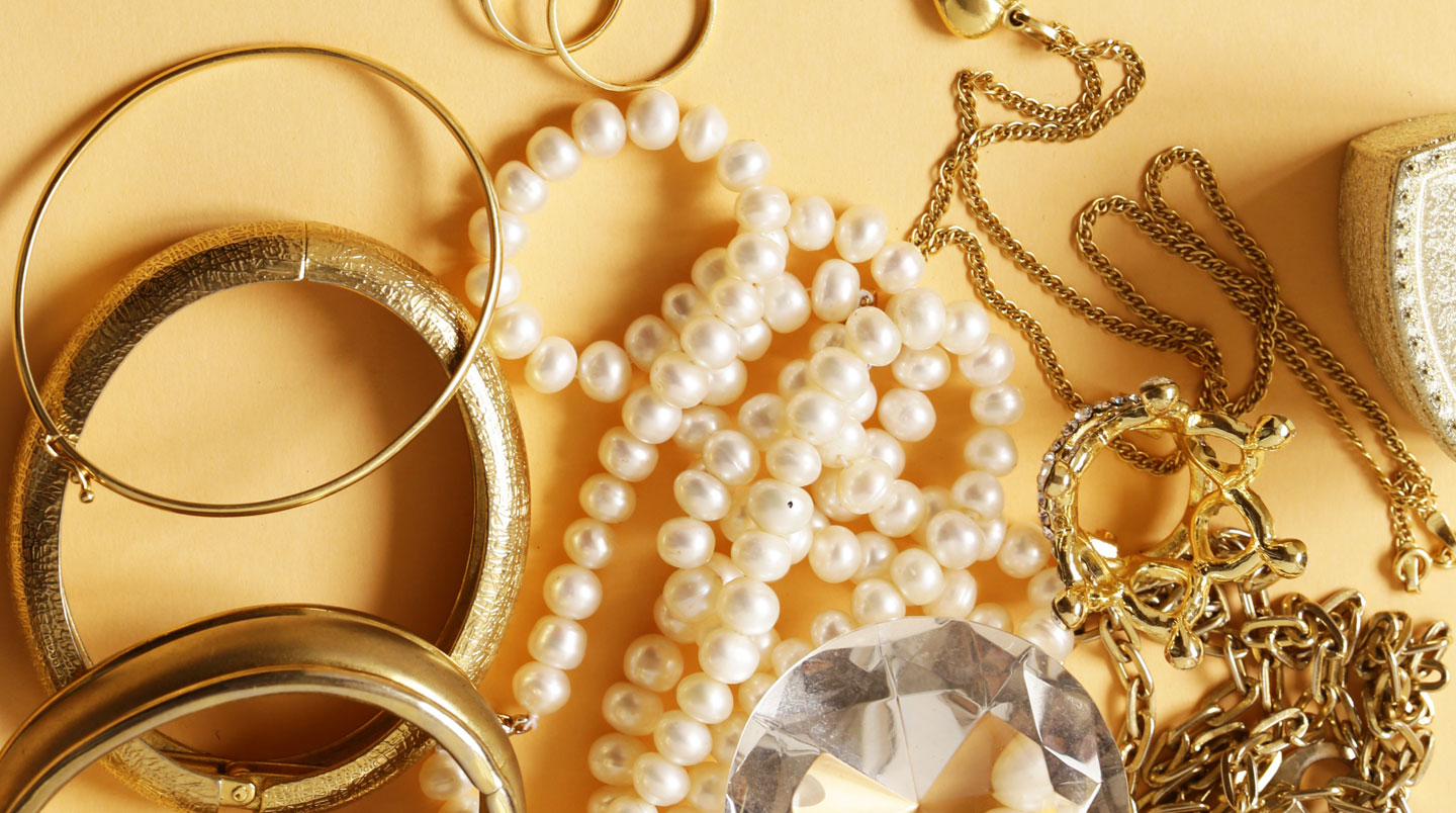 Vue du dessus de trois rangées alignées de bracelets joncs en or jaune, argent et or rose sur bois clair, illustrant le layering métallique